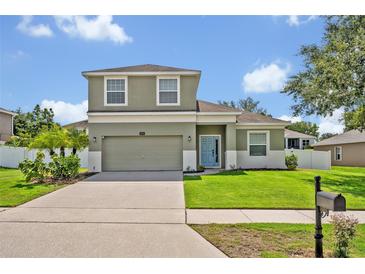 Charming two-story home with a well-manicured lawn, a two-car garage, and a light-blue front door at 11616 Thacker Dr, Clermont, FL 34711