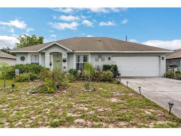 Charming single-story home with a two-car garage and lush garden in the front yard at 1907 Myakka Ct, Poinciana, FL 34759