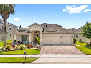 Charming single-story home with a three-car garage and well-manicured landscaping and a brick paved driveway at 2051 Sandy Garden Ln, Winter Garden, FL 34787