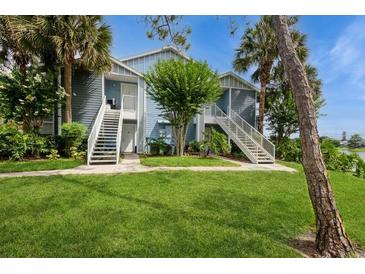 Inviting exterior featuring a well-maintained blue condo with lush landscaping and a staircase leading to the entrance at 2501 Grassy Point Dr # 107, Lake Mary, FL 32746