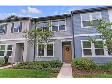 Charming two-story townhome with a welcoming yellow door and well-maintained landscaping at 3028 Water Sprite St, Orlando, FL 32808