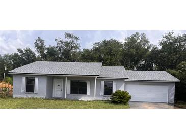 Charming single-story home with gray exterior, white trim, and a one-car garage in a serene, wooded setting at 1050 Reading Ct, Winter Park, FL 32792