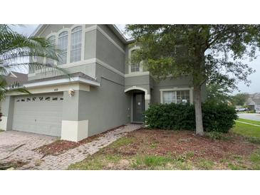 Two-story home featuring neutral paint and a welcoming front entrance with brick path and a manicured lawn at 14508 Cedar Branch Way, Orlando, FL 32824