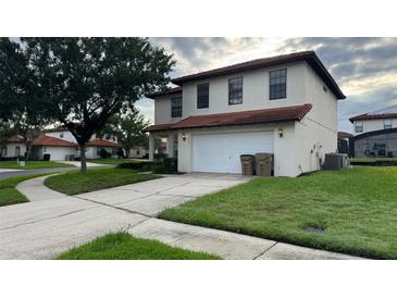 Two story home featuring a white exterior, tile roof, two car garage, and a well manicured front yard at 16631 Lazy Breeze Loop, Clermont, FL 34714