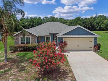 Charming single-story home with stone accents, a two-car garage and flowering bushes at 382 Lake St, Umatilla, FL 32784