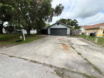 Charming home featuring a gray exterior, a spacious driveway, and mature trees at 6849 Palomino Dr, Lakeland, FL 33811