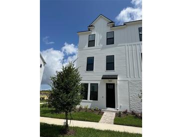 Charming three-story townhome with a modern white facade and a well-manicured front lawn at 15107 Grove Lake Dr, Winter Garden, FL 34787