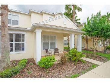Charming townhouse with a covered front porch, lush landscaping, and two outdoor chairs at 17516 Blessing Dr, Clermont, FL 34714