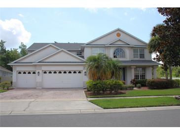 Stunning two-story home with a three-car garage, paver driveway, manicured lawn, and lush landscaping at 2543 Chapala Dr, Kissimmee, FL 34746