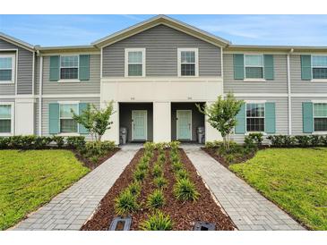Charming townhome featuring a landscaped walkway leading to the front door with teal shutters and gray siding at 720 Gardenia Ln, Davenport, FL 33897