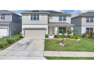 Charming two-story home with a well-manicured lawn, solar panels, a two-car garage, and a welcoming front porch at 7639 Agrigento St, Clermont, FL 34714