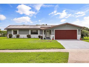 Charming single-story home with a well-manicured lawn, solar panels, and an attached two-car garage at 930 Chickadee Dr, Port Orange, FL 32127