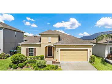 Charming single-story home with tan exterior, a two-car garage, and neatly manicured landscaping at 12216 Prairie Plantation Way, Orlando, FL 32824