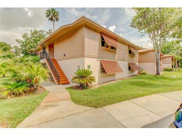 Inviting two-story condo featuring shuttered windows, manicured lawn, mature trees, and a cozy staircase to the entrance at 150 Wax Myrtle Woods Ct # 3D, Deltona, FL 32725