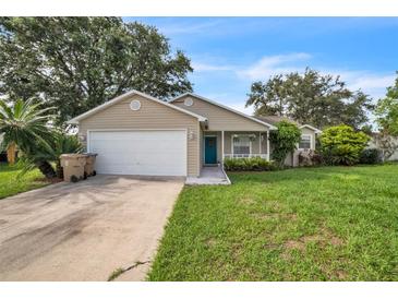 Charming single-story home featuring a manicured lawn, attached garage, and inviting blue front door at 1840 Orange View Ct, Kissimmee, FL 34746