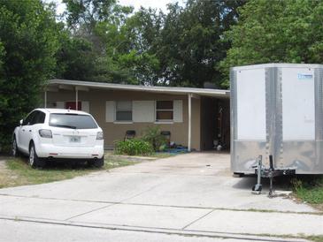 Modest one-story home featuring neutral exterior, small yard, carport, and a private driveway at 5112 Figwood Ln, Orlando, FL 32808