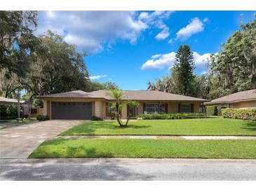 Well-manicured home featuring a spacious front yard, long driveway, and attached two car garage at 7852 Broken Arrow Trl, Winter Park, FL 32792