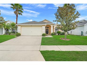 Charming single-story home with a well-maintained lawn, palm tree, and two-car garage at 915 Lockbreeze Dr, Davenport, FL 33897