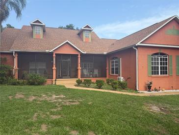 Charming single-story home with a screened-in porch, lush lawn, and colorful exterior paint scheme at 1031 Kings Hwy, Kissimmee, FL 34744