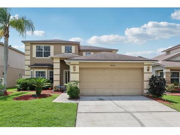 Inviting two-story home featuring a manicured lawn, attached two-car garage, and desert landscaping at 14680 Yorkshire Run Dr, Orlando, FL 32828