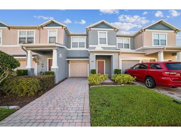 Charming townhome featuring a one-car garage, brick pathway, and well-maintained front lawn at 16449 Cedar Crest Dr, Orlando, FL 32828