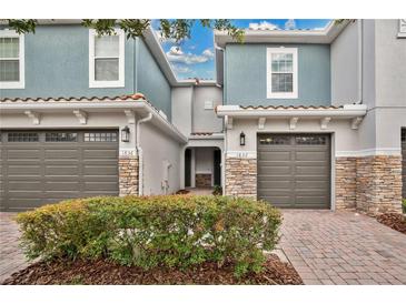 Charming townhouse featuring a gray facade, stone accents, and a well-manicured landscape at 1852 Garden Sage Dr, Oviedo, FL 32765