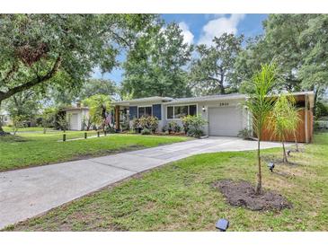 Charming single-story home featuring a well-manicured lawn, complemented by mature trees and a concrete driveway at 2910 Hargill Dr, Orlando, FL 32806