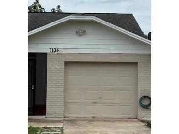 Attached one car garage with a door and house number 7104, with a brick facade under a white roof at 7104 Blue Earth Ct, Orlando, FL 32818