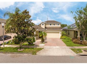 Charming home features a well-manicured lawn, brick driveway, and inviting facade at 7214 Tattant Blvd, Windermere, FL 34786