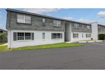 Two-story condo featuring a gray shingled roof, white siding, and reserved parking spaces at 1000 S Semoran Blvd # 604, Winter Park, FL 32792
