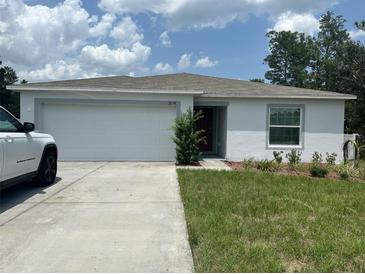 Charming single-story home featuring a two-car garage, a well-kept lawn, and a classic neutral-toned exterior at 2136 Hibiscus Pl, Kissimmee, FL 34759