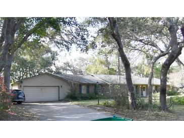 Charming single-story home with a two-car garage, surrounded by mature trees and lush landscaping at 220 Morton Ln, Winter Springs, FL 32708