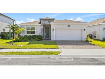 Charming single-story home with a stone facade, a two-car garage, and a well-manicured lawn at 3123 Camden Way, Davenport, FL 33837