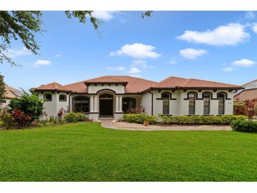Charming one-story home with lush green lawn, terracotta tile roof, and well-manicured landscaping at 12663 Hawkstone Dr, Windermere, FL 34786