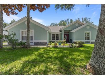 Charming one-story home featuring a lush green lawn and inviting curb appeal with stone accents and mature trees at 36646 Oconee Ave, Eustis, FL 32736