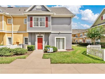 Charming townhome featuring a vibrant red door and neutral gray siding, surrounded by lush green landscaping at 4600 Yellowgold W Rd # 102, Kissimmee, FL 34746