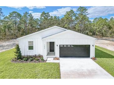 Charming one story home with white siding, black garage door, and a well manicured lawn at 7520 Sw 134Th Ave, Dunnellon, FL 34432