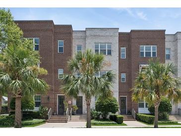 Charming multi-story townhomes with brick and white brick exteriors, complemented by lush landscaping and palm trees at 464 W Plant St, Winter Garden, FL 34787