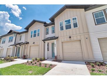 Modern townhome featuring neutral paint, attached garages, and well-maintained landscaping against a bright blue sky at 832 Longboat Dr, Davenport, FL 33896