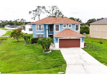 Two-story home featuring a lawn with palm trees, and a large garage at 1001 Dampierre Ct, Kissimmee, FL 34759
