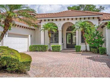 Charming home featuring a brick paved driveway, arched entryway, and mature landscaping at 11015 Hawkshead Ct, Windermere, FL 34786