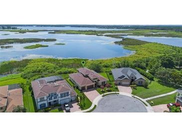 Stunning aerial view of waterfront homes in a cul-de-sac neighborhood with lush greenery and lake views at 15344 Johns Lake Pointe Blvd, Winter Garden, FL 34787