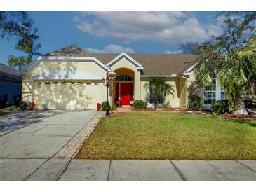 Inviting single-story home with a well-manicured lawn, mature landscaping, and a vibrant red front door at 1662 Canoe Creek Rd, Oviedo, FL 32766
