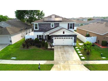 Charming two-story home featuring stone accents, solar panels, a well-maintained lawn, and a two-car garage at 208 Oleander St, Winter Haven, FL 33881