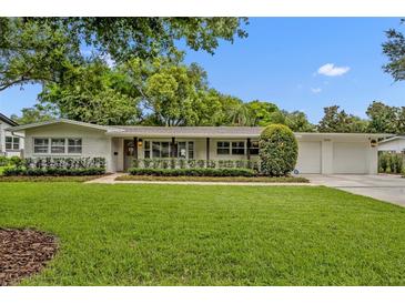 Charming brick home featuring a two-car garage, lush green lawn, and decorative landscaping at 2112 Fosgate Dr, Winter Park, FL 32789