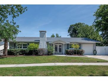 Charming one story home boasts a well-manicured lawn, mature landscaping, and neutral color palette at 2325 E Harding Street, Orlando, FL 32806
