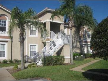 Charming condo featuring a two-story entrance and beautifully maintained landscaping with mature palms at 2826 Osprey Cove Pl # 103, Kissimmee, FL 34746
