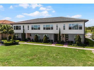 Modern townhome featuring a well-manicured lawn, symmetrical landscaping, and expansive windows for great natural light at 10108 Sunnifa Aly, Orlando, FL 32832