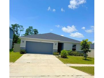 A charming single-story home featuring a well-maintained lawn and a two-car garage on a sunny day at 1557 Venice Ln, Davenport, FL 33896