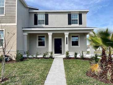 Charming two-story home featuring well-manicured lawn and inviting entrance with a concrete path at 15579 Water Spring Blvd, Winter Garden, FL 34787